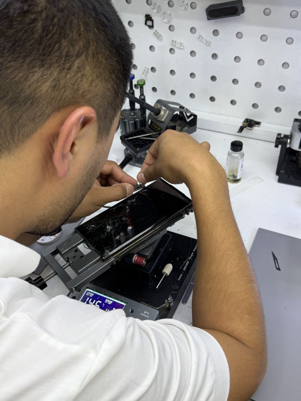 Usta telefon ekranini maxsus uskunada ta’mirlamoqda